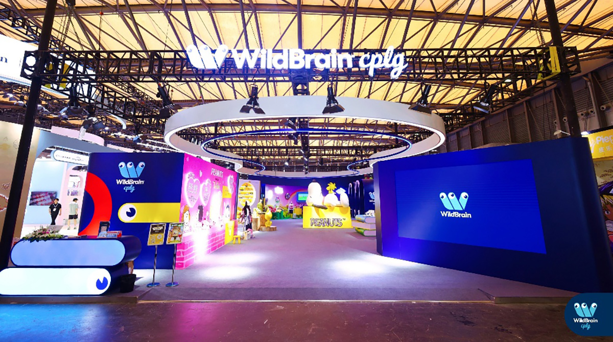 贸易展位以花生品牌为主题，配有丰富多彩的图形设计，上方大型结构悬挂着WildBrain CPLG标志。