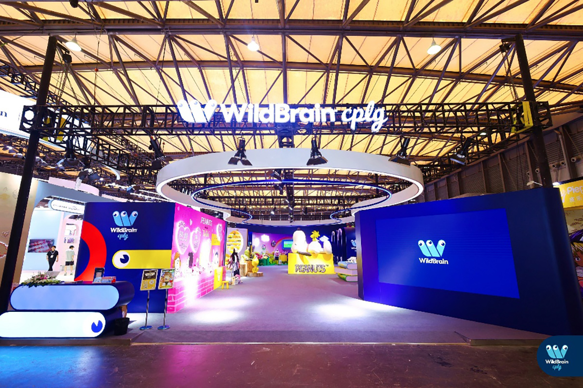 贸易展位以花生品牌为主题，配有丰富多彩的图形设计，上方大型结构悬挂着WildBrain CPLG标志。